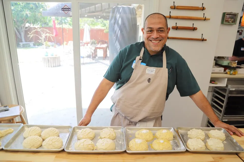 Nacho Varela smiling behind sheet trays of conchas in a test kitchen