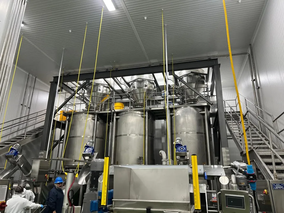 Stainless-steel batch tanks and hoppers on a mezzanine in a food plant
